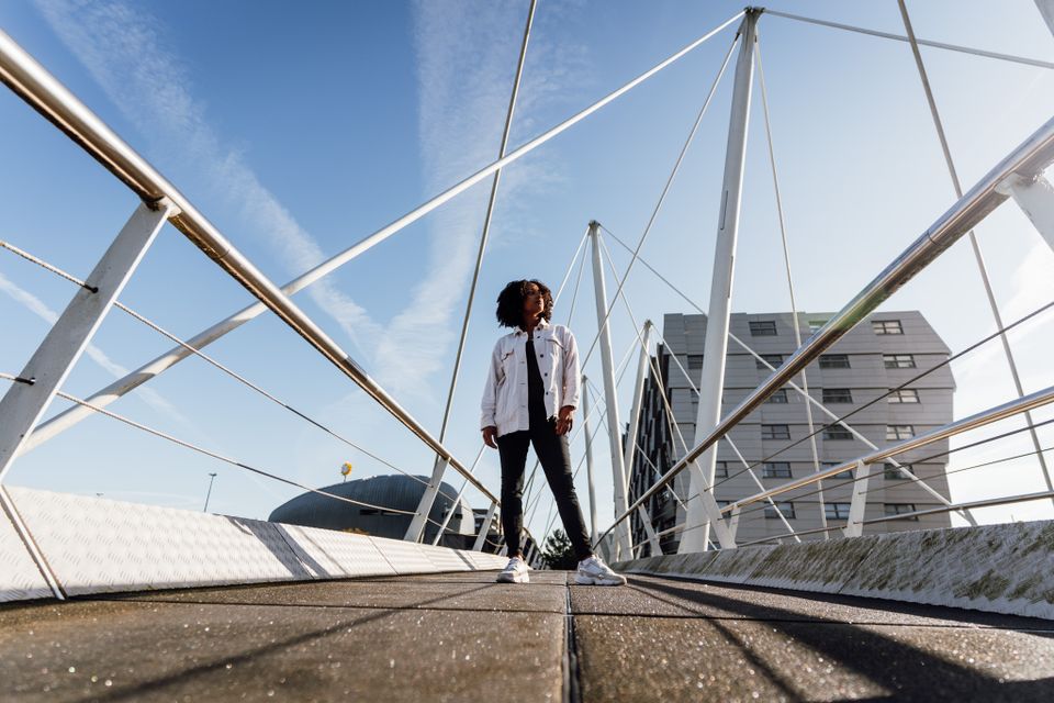 Vrouw op moderne brug in Almere met strakblauwe lucht